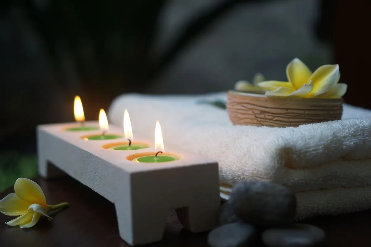 Velas encendidas, toallas y flores de frangipani
